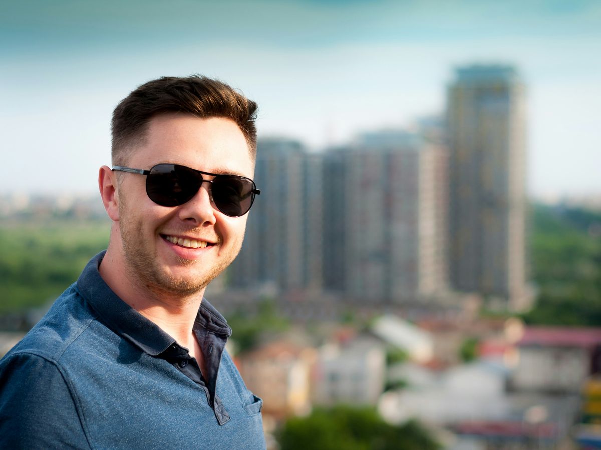 man wearing blue polo shirt with building background