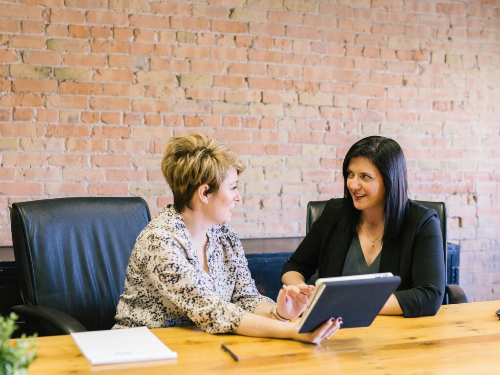 two women sitting on leather chairs in front of table